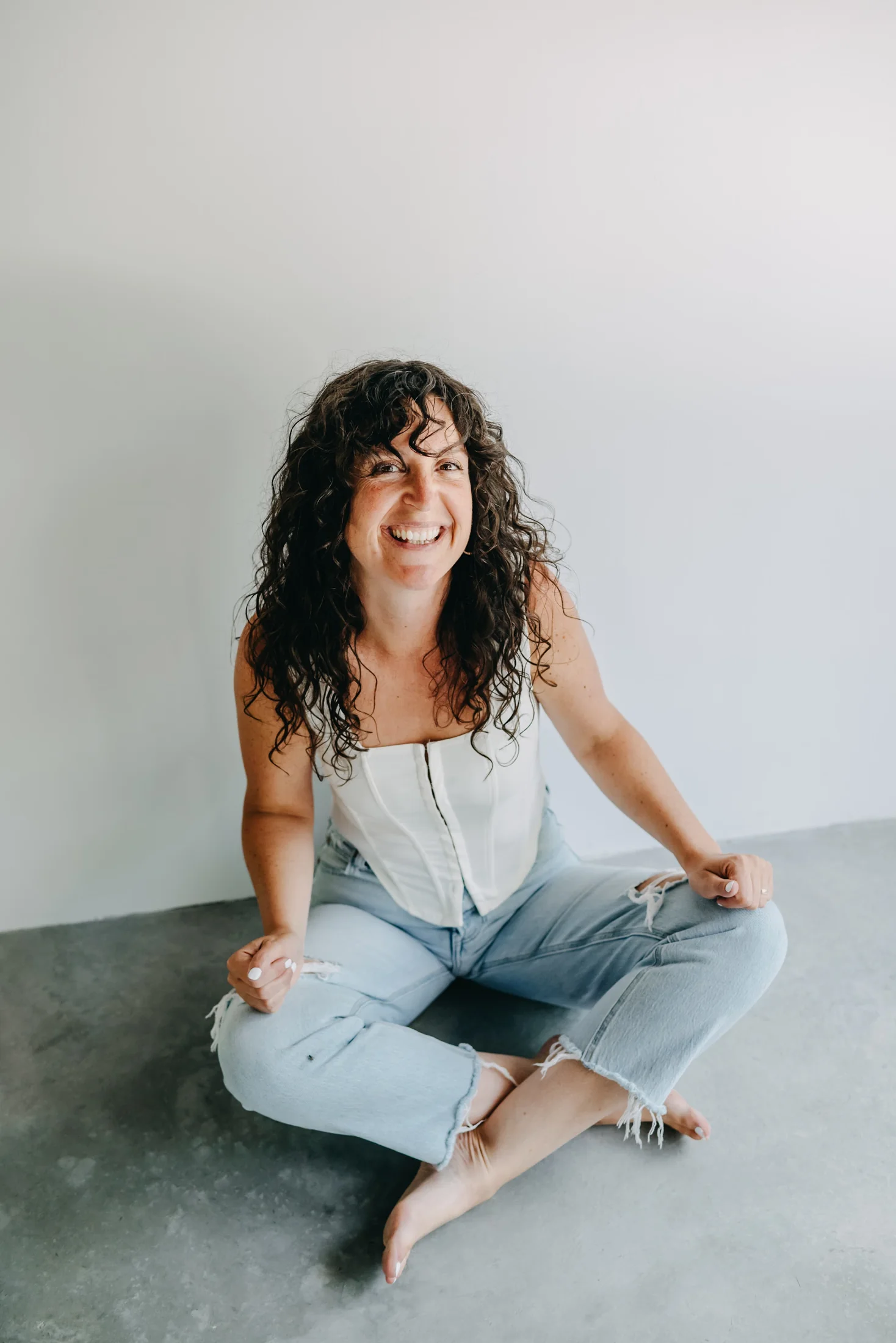 Shelby seated cross-legged on the floor, laughing